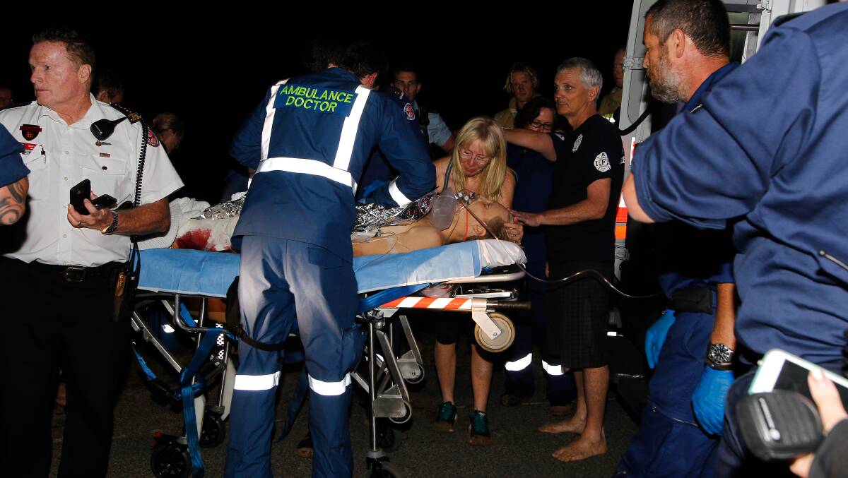  Paramedics and family members surround Brett Connellan in the aftermath of his ordeal at Bombo Beach. Picture: Sylvia Liber