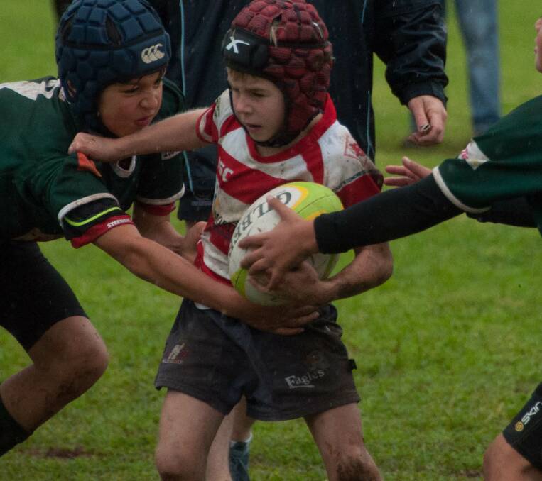 Drew Langfield pushes the defence aside and continues his run on a muddy surface at the Cowra rugby grounds.