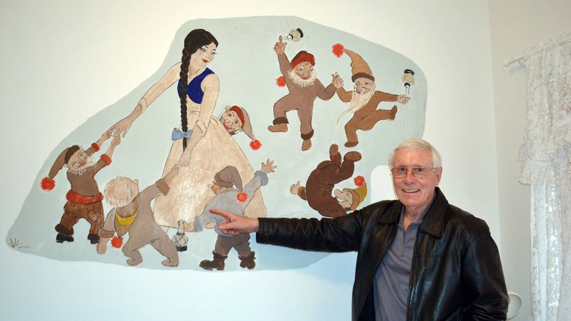 Bill Ticehurst pointing to the damage he caused to the mural as a boy.