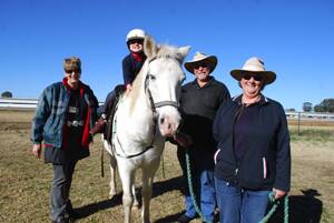 Volunteers Julie Thoms and Carol and Dudley Nicholson help as Mathew Lindsay rides 'Kimba'.