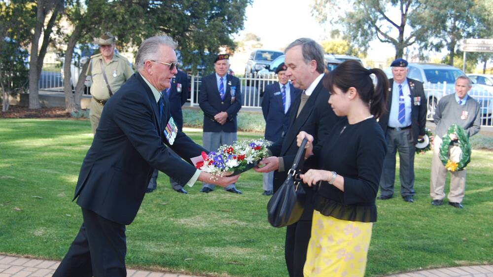 Cowra RSL Sub-Branch's Frank Bridges hands a wreath to Lawrance Ryan and Dr Noriko Tanaka of Japan's Consulate-General in Sydney.
