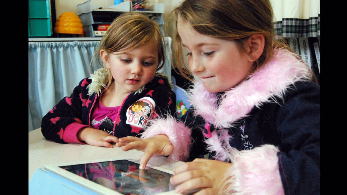 Kelly Smith (left) has her first speech pathology session with the new ipad while big sister Amber also has a turn.