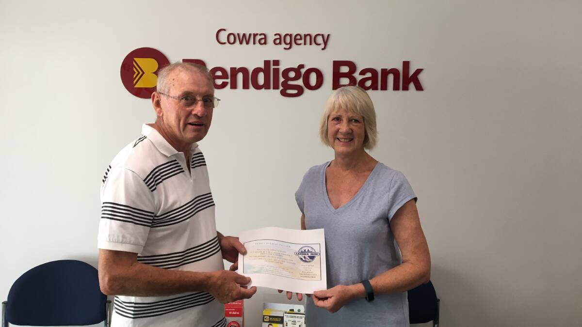 Cowra Rotary Club President Brian Marsh presenting well known local Janine Robinson with her holiday voucher.