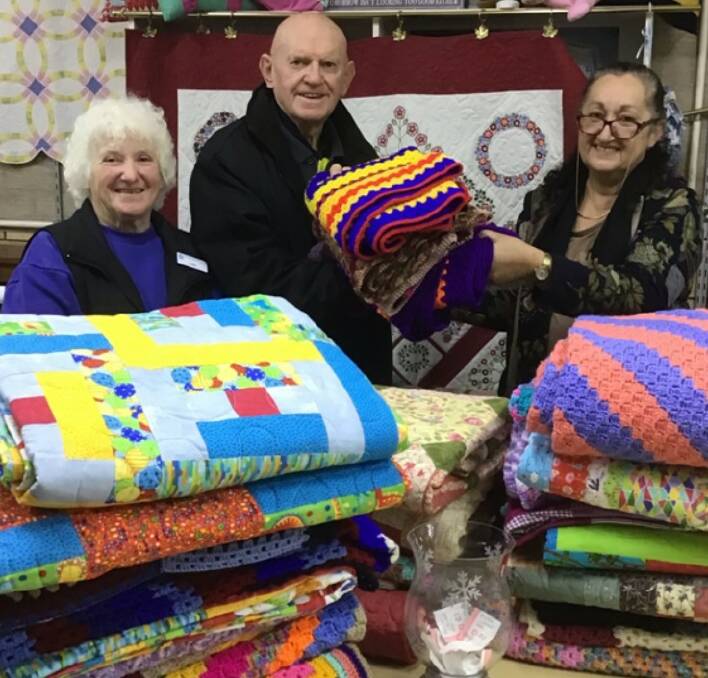 Dawn Beath and Len Ryan of St Vincent de Paul accepting quilts from Joanne Cameron, who made the donation on behalf of the Cowra Sewing Group.