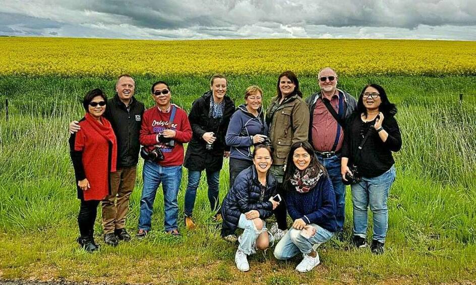 Tourists pictured in front of a canola crop on one of Cowra Tourism's organised Canola tours.
