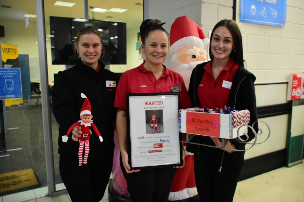 Coles Cowra team members Jemma Pokoney, Nadia Cherry and Maisie Thompson with Cole the Elf, his "Wanted" poster and a sleigh full of sweet treats as rewards for finding the elf. 