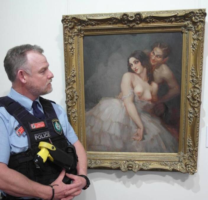 Inspector Adam Beard from Cowra Police looks at Woman with Satyr by renowned Australian artist, Norman Lindsay. 
