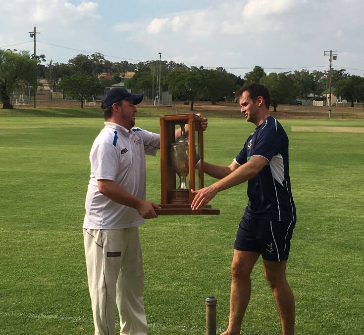 Cowra cricket captain Nick Berry accepts the Grinsted Cup from Parkes captain Anthony Heraghty during the 2018 match.