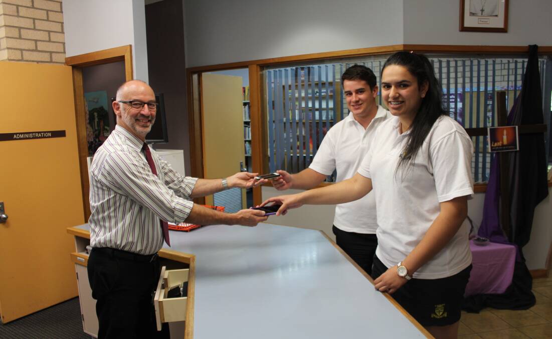  Principal Michael Gallagher accepts smartphones from students Matthew Prescott and Parneet Kaur.