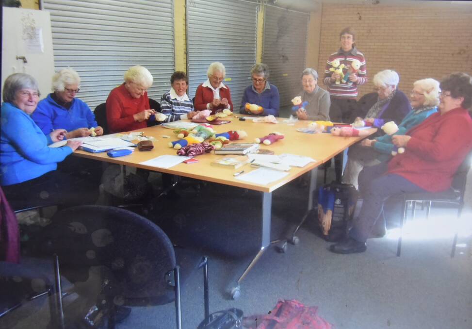 Members of the Morongla Red Cross sewing Red Cross tags on bears.