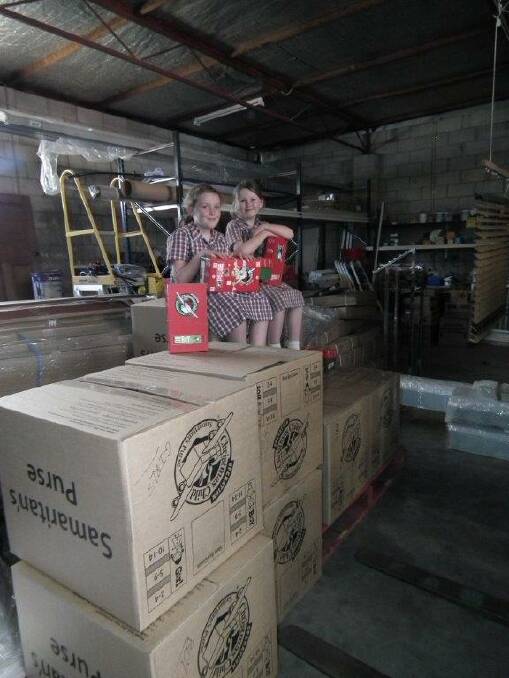 Melissa and Sarah Curtis sit atop the waiting cartons of Operation Christmas Child boxes last year.