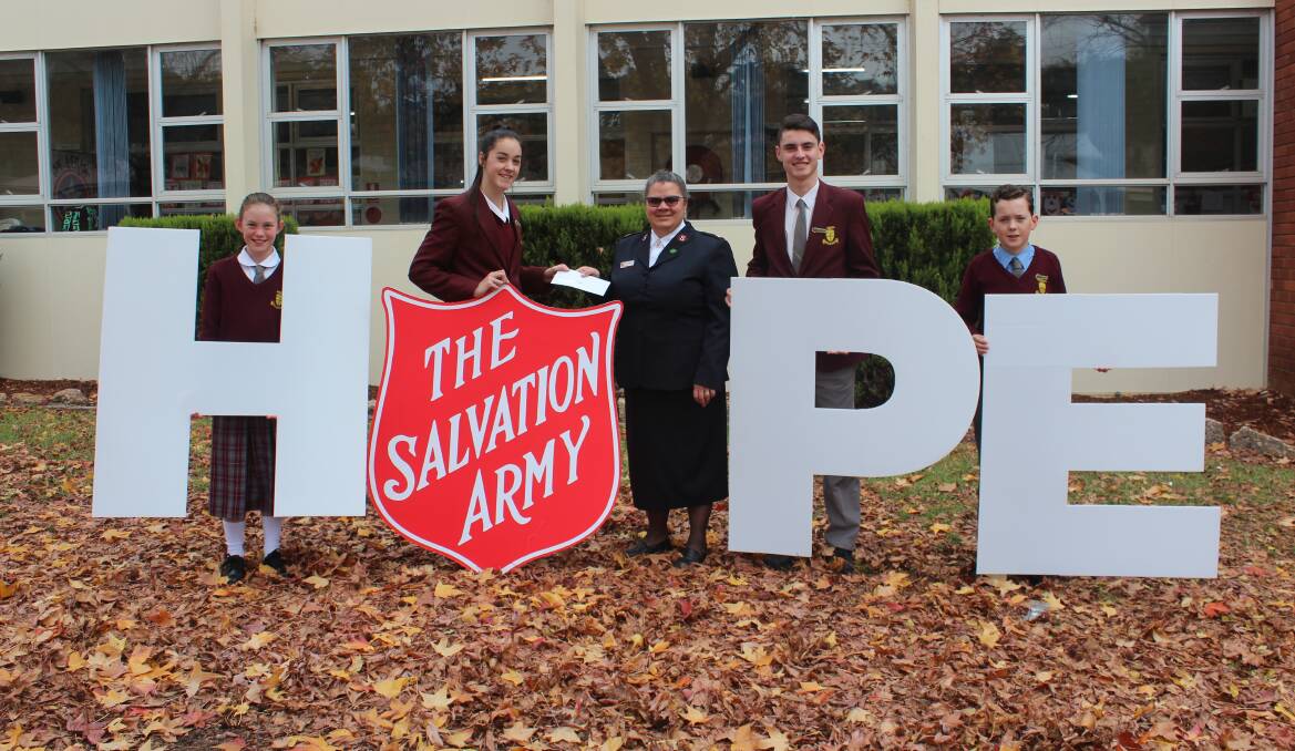 Grace Gallagher (second left) presents Major Cathryn Williamson with the school's donation with help from Kaitlyn Rutledge, Aiden Roberts and Orlando Perry.