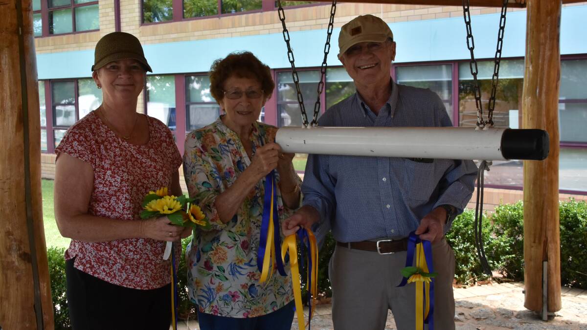 World Peace Bell Association committee members Maggie Wright, Jan Monday and Ian Brown decorating the peace bell.