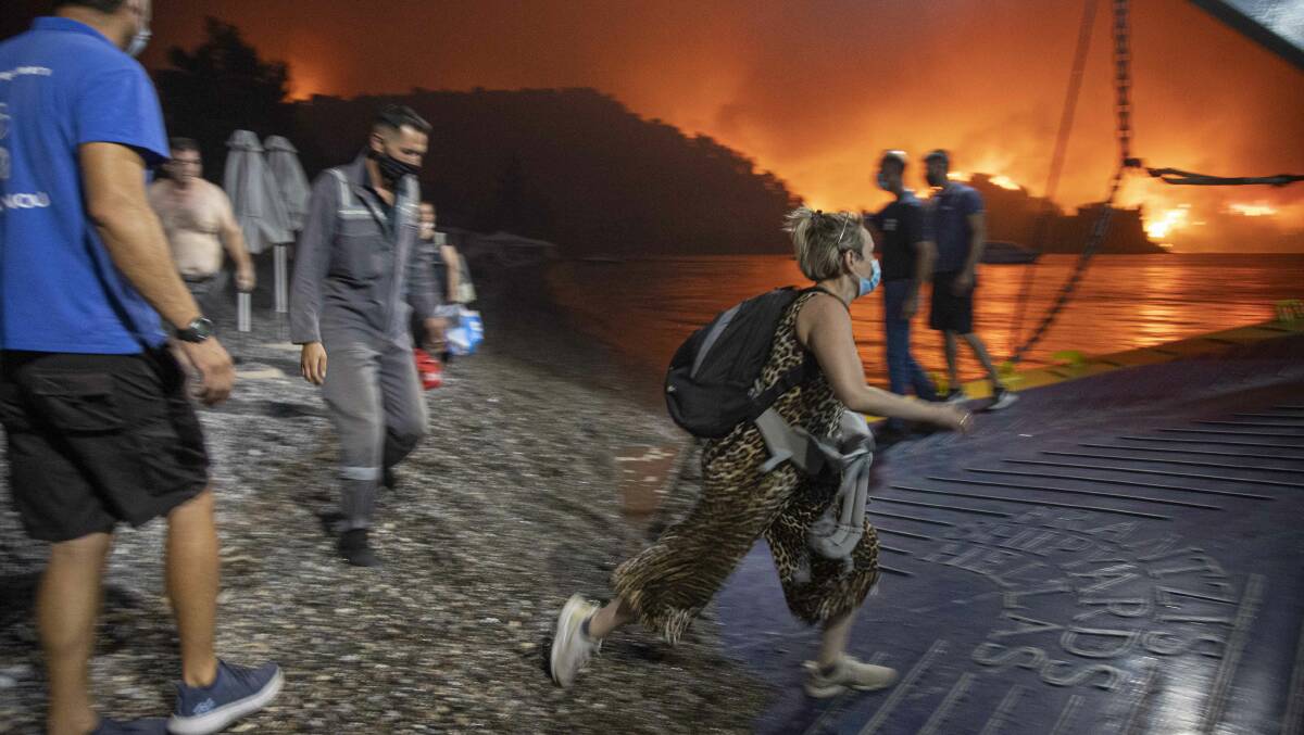 People board a ferry prior to an evacuation as a wildfire approaches the seaside village of Limni, on the island of Evia, Greece, on Friday. Picture: Getty Images