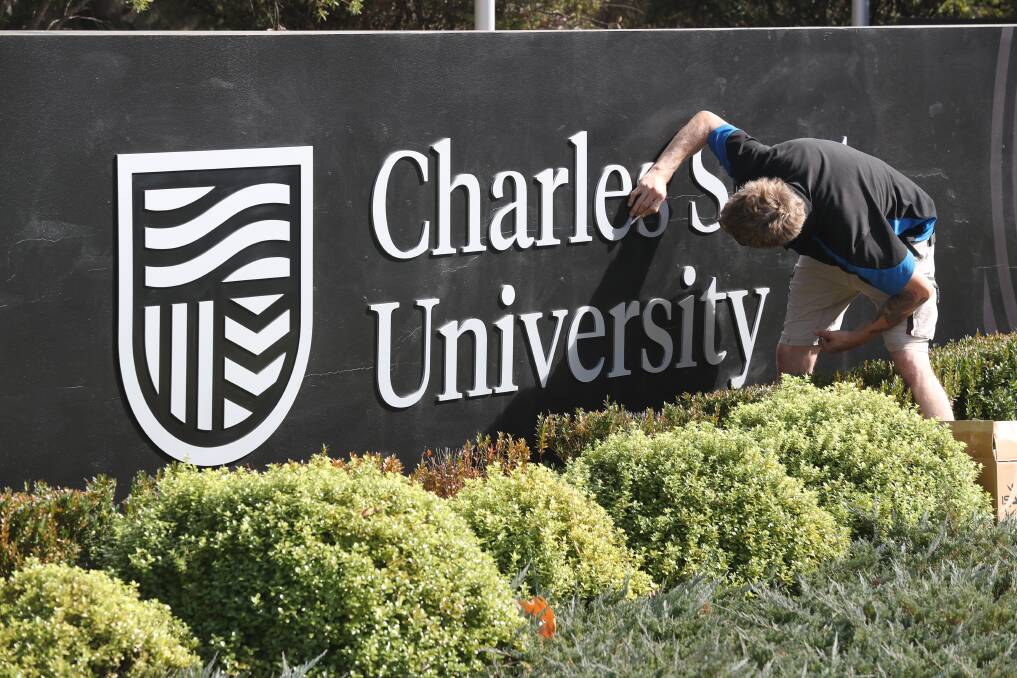 NEW LOOK: Workers installing the new logo sign at one of Charles Sturt University's Central West campuses on Wednesday morning. Photo: PHIL BLATCH 050119pbcsu2