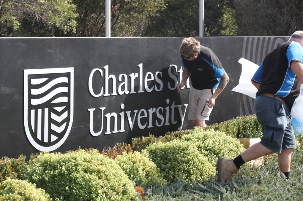 NEW LOOK: Workers installing the new logo sign at one of Charles Sturt University's Central West campuses on Wednesday morning. Photo: PHIL BLATCH 050119pbcsu1